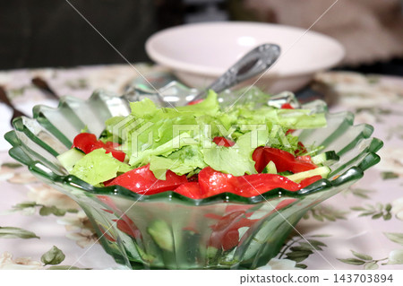 Clear glass salad bowl containing a salad of fresh vegetables and herbs Clear glass salad bowl containing a salad of fresh vegetables and herbs 143703894