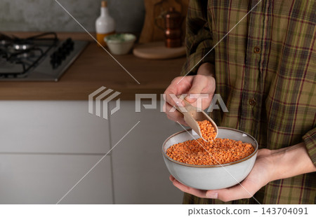 Hands Holding Bowl of Red Split Lentils with Wooden Scoop Hands Holding Bowl of Red Split Lentils with Wooden Scoop 143704091