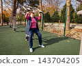 Mature Caucasian woman performs gentle workout outdoors after medical treatment. Rehabilitation, prevention of complications, and active senior lifestyle. 143704205
