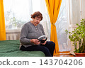 Senior woman dancing freely while listening to favorite tracks at home. Cheerful energy and comfort. Concept of active aging lifestyle. 143704206