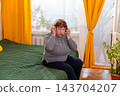 Older female enjoying music entertainment and rhythmic movement indoors. Relaxed retirement and positivity. Concept of elderly hobbies. 143704207