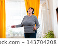 Senior Caucasian woman dancing during leisure time in cozy interior. Happiness and freedom. Concept of active senior living. Mid shot 143704208