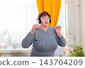 Elderly female spending evening dancing to favorite playlist at home. Positive emotions and relaxation. Concept of active hobbies. Mid shot 143704209