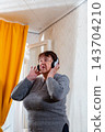 Older Caucasian woman dancing casually while enjoying favorite songs. Emotional comfort and happiness. Concept of pensioner leisure. Vertical 143704210