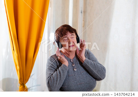 Senior Caucasian woman enjoying active leisure with music indoors. Freedom and cheerful mood. Concept of healthy senior routine. Mid shot 143704214