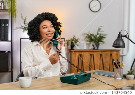 African American businesswoman laughs talking on retro old phone smiling kindly during client call African American businesswoman laughs talking on retro old phone smiling kindly during client call 143704540