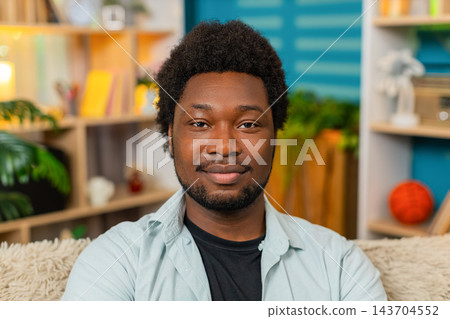 African American young man on home sofa looking at camera with gentle smile in calm portrait scene African American young man on home sofa looking at camera with gentle smile in calm portrait scene 143704552