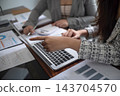 Cropped image of professional businesswoman, entrepreneur or accountant working on a financial report paperwork at her desk, using calculator or laptop 143704570