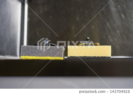 Two cleaning sponges rest side by side inside stainless steel kitchen sink Two cleaning sponges rest side by side inside stainless steel kitchen sink 143704928