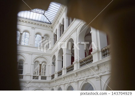 View through dark archway toward interior courtyard with arcades, balustrades and glass roof View through dark archway toward interior courtyard with arcades, balustrades and glass roof 143704929