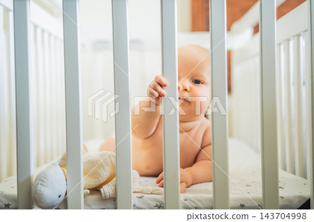 Curious infant exploring the cot during independent awake time. Curious infant exploring the cot during independent awake time. 143704998