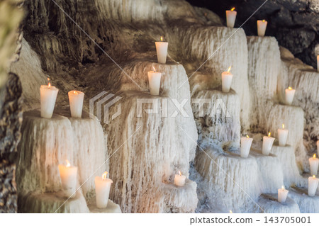 Burning votive candles above thick layers of melted wax in a devotional display. Burning votive candles above thick layers of melted wax in a devotional display. 143705001