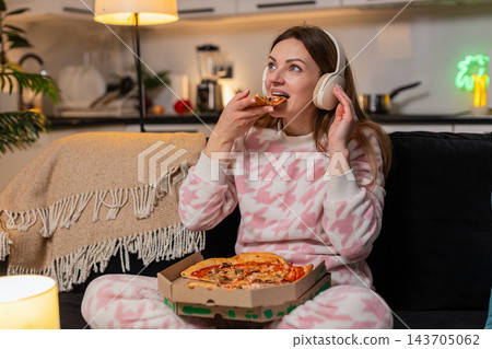 Adult woman dances with headphones at night enjoys music eats pizza smiles freedom happy cozy moment 143705062