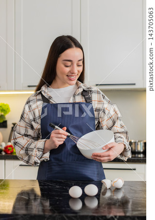 Young woman cracking eggs in kitchen bowl preparing simple breakfast omelet or baking dough at home Young woman cracking eggs in kitchen bowl preparing simple breakfast omelet or baking dough at home 143705063