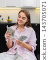 Young woman counts cash dollars smiles about salary savings plans big dream purchase and investments 143705071