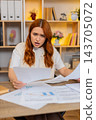 Young woman on home table sorting papers and feeling stressed by confusing household paperwork mess 143705072