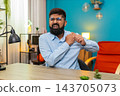 Indian man clutching painful shoulder injury sharp discomfort strained muscle seeking relief indoors 143705073