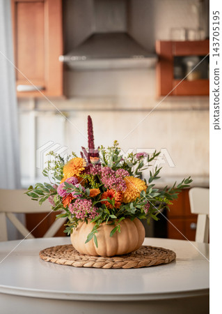 Autumn flower arrangement in pumpkin vase in cozy kitchen interior 143705195