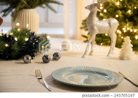 Elegant Christmas table setting with glowing tree lights Elegant Christmas table setting with glowing tree lights 143705197