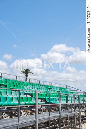 Empty Green Stadium Bleachers Under Blue Sky 143705404