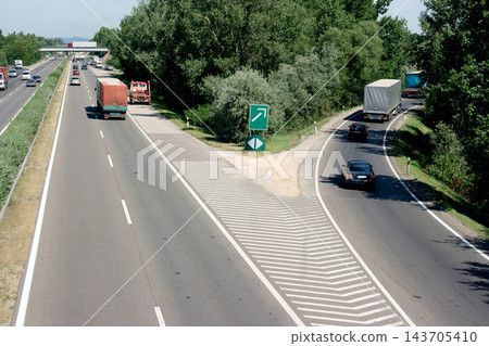 Highway Exit with Traffic, Trucks, Cars and Green Road Sign Highway Exit with Traffic, Trucks, Cars and Green Road Sign 143705410