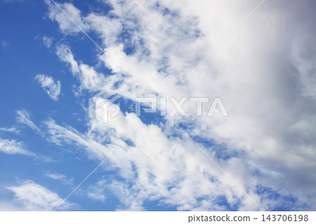 White cumulus and wispy cirrus clouds spread across a blue sky. White cumulus and wispy cirrus clouds spread across a blue sky. 143706198