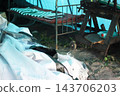An old metal bed with a wire mesh frame and curved headboards stands among discarded items in an outbuilding. 143706203