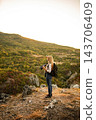 Young woman hiking in mountains holding binoculars looking view 143706409