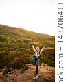 Woman hiker celebrating success on mountain peak at sunset 143706411
