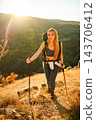 Young woman hiking mountain trail using trekking poles 143706412
