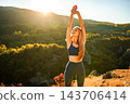 Woman stretching arms up during beautiful sunset outdoors 143706414