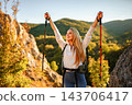 Woman hiking mountains celebrating success with arms raised 143706417