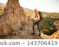 Happy young woman hiking in mountains using trekking poles 143706419