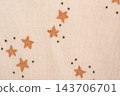 Beige knitted fabric with brown stars macro photo as background. Macro photo of children's clothing. 143706701
