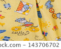 Clothes as a background in yellow with a children's print, macro photo. 143706702