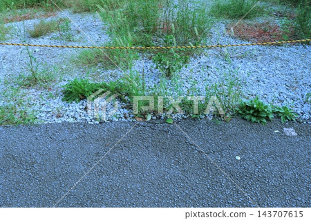 瀝青路與鋪滿碎石的空地之間用安全繩隔開的邊界(房地產/道路邊界圖) 瀝青路與鋪滿碎石的空地之間用安全繩隔開的邊界(房地產/道路邊界圖) 143707615