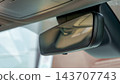 Close up of a vehicle rearview mirror reflecting the interior roof and seats inside a modern car cabin 143707743