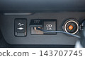 Close up view of vehicle dashboard with USB port, power socket, charging adapter, and connected cable in dark interior 143707745