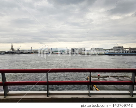 Industrial Port Area and Waterfront Skyline Across Osaka Bay Viewed Behind Red Metal Railing in Izumiotsu, Osaka, Japan. Industrial Port Area and Waterfront Skyline Across Osaka Bay Viewed Behind Red Metal Railing in Izumiotsu, Osaka, Japan. 143709748