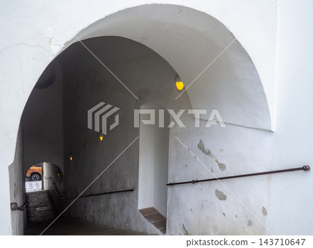 A white vaulted archway leading into a sloped underground tunnel or passage A white vaulted archway leading into a sloped underground tunnel or passage 143710647
