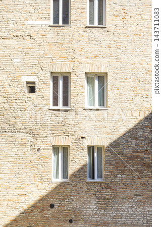 A brick wall features several windows and a diagonal shadow in Urbino, Italy A brick wall features several windows and a diagonal shadow in Urbino, Italy 143711083