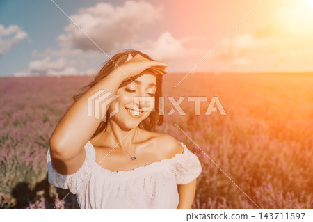 Lavender woman sunset shielding her eyes from the sun in a flowering field during golden hour under a blue sky Lavender woman sunset shielding her eyes from the sun in a flowering field during golden hour under a blue sky 143711897