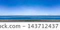 A long, horizontal coastal landscape overlooking the blue sky and calm sea on a sunny day. 143712437
