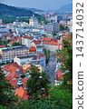 A vertical view of the townscape with red roofs and the surrounding mountains. 143714032