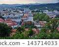 The rooftops of the old town and the distant mountain range can be seen through the green trees. 143714033