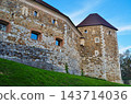 Stone castle walls and corner towers against a blue sky 143714036