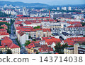 A view overlooking a residential area with red roofs stretching along a street. 143714038