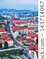 A cityscape with red roofs and distant mountains viewed in portrait orientation. 143714067