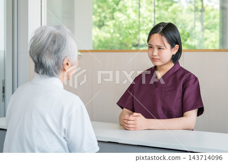 一位年輕的女護理員在養老院諮詢台為老年女性提供支援。 143714096