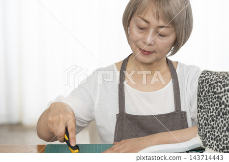一位老婦人在客廳裡改造了一個娃娃椅,作為她的DIY愛好。 一位老婦人在客廳裡改造了一個娃娃椅,作為她的DIY愛好。 143714443